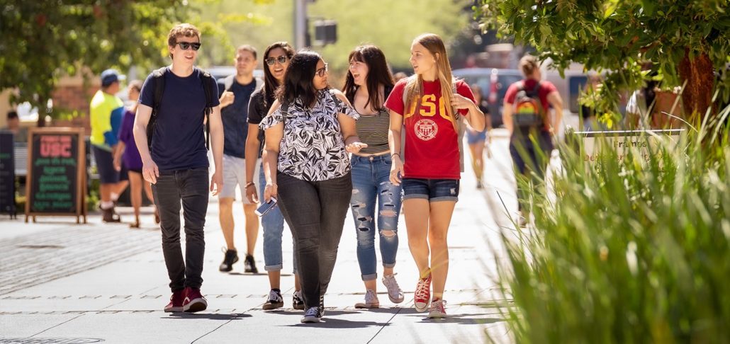 students walk together outside on campus