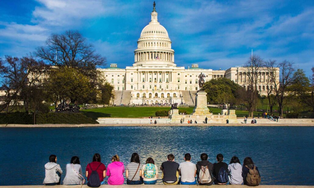 USC students sit across a reflecting pool from the United States Capitol building