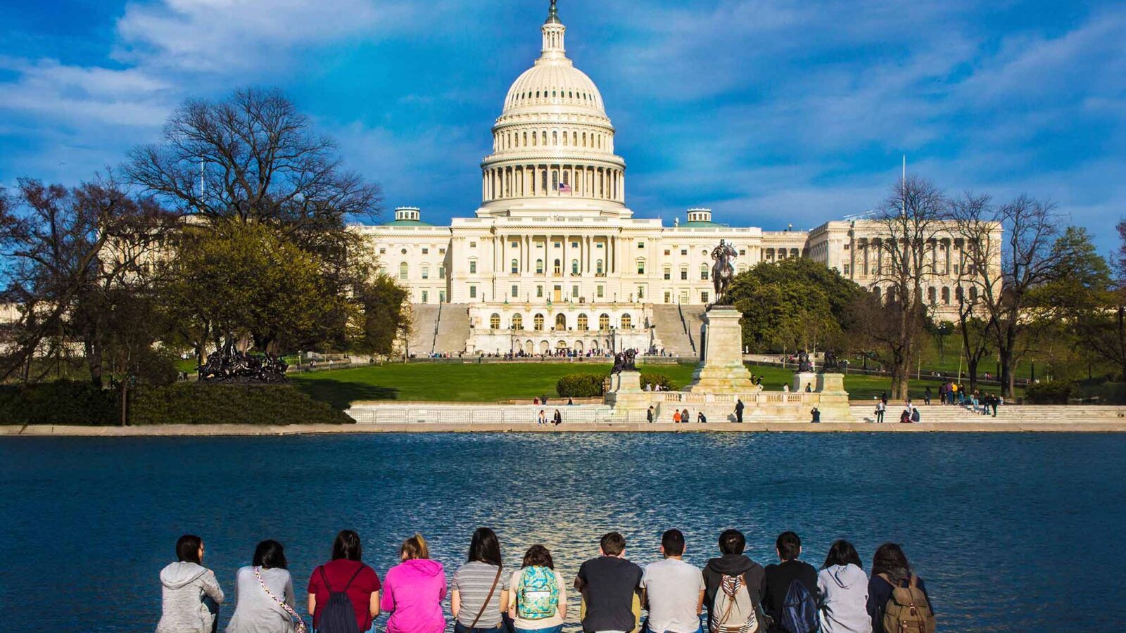 USC students sit across a reflecting pool from the United States Capitol building